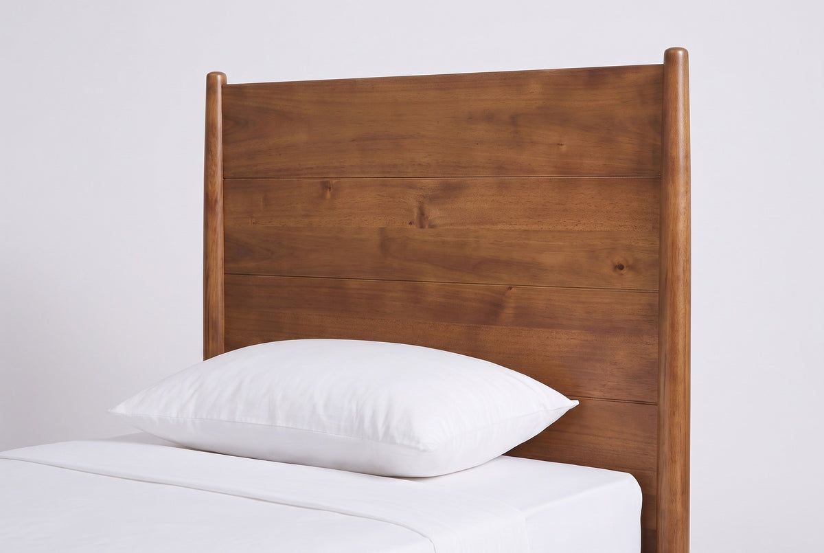 One side of the Agnone headboard: a slim round post with a rounded top beside the flat panel of horizontal acacia boards, above a white pillow