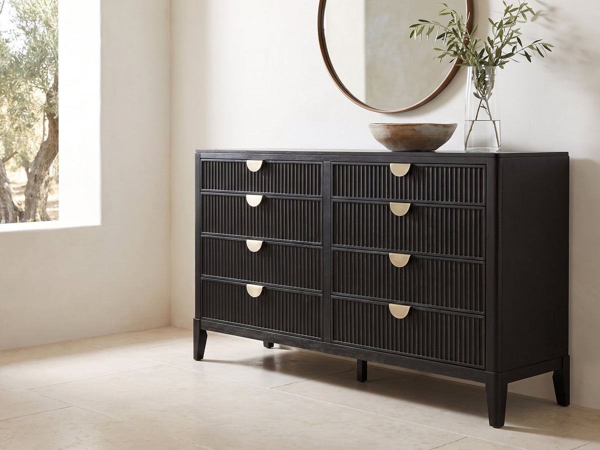 Agordo 66-Inch Black Fluted 8-Drawer Dresser under a round bronze mirror in a villa bedroom