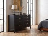 Agordo 66-Inch Black Fluted 8-Drawer Dresser against a plaster wall in an industrial loft bedroom