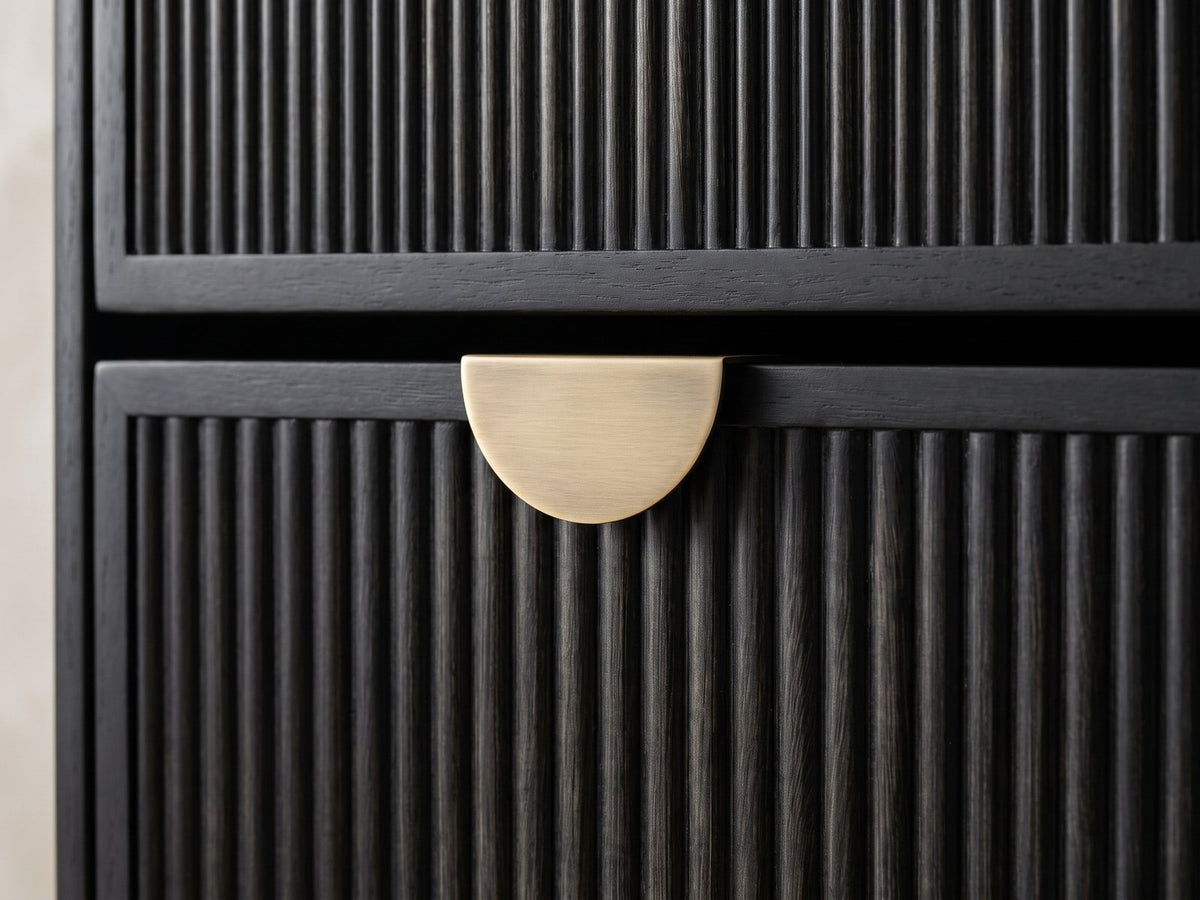 Close-up of the Agordo 66-Inch Black Fluted 8-Drawer Dresser: the brass-finish half-moon pull on the black fluted drawers