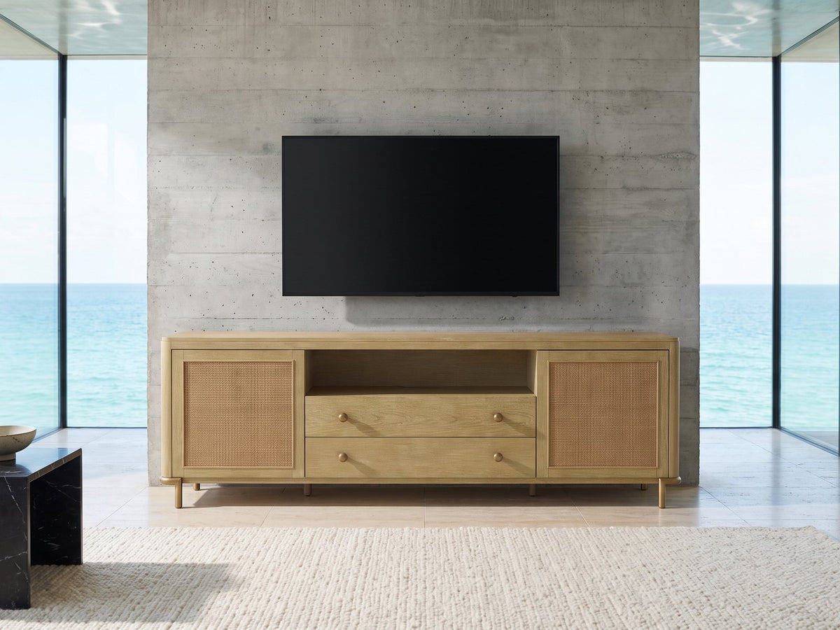 Alassio 80-Inch Sand Wash Ash and Rattan Media Console under a wall-mounted screen in an oceanfront glass house
