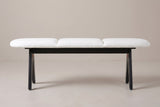 The Alatri bench with a white fabric seat and black legs, side view on a light studio backdrop