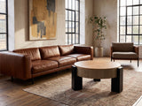 Alba 31.5-Inch Round Parquet Wood Veneer Storage Coffee Table on a vintage rug in front of a leather sofa in an industrial loft