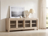 Albenga 71-Inch Weathered Mango Veneer Sliding Glass Door Media Console styled with a leaning print, a lamp and ceramics in a bright plaster room