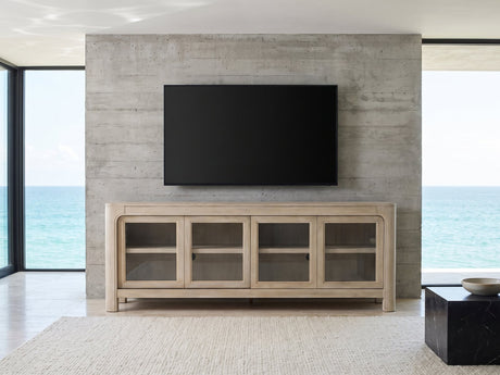 Albenga 71-Inch Weathered Mango Veneer Sliding Glass Door Media Console under a wall-mounted screen in an oceanfront glass house
