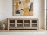 Albenga 71-Inch Weathered Mango Veneer Sliding Glass Door Media Console under a large abstract painting in a bright living room