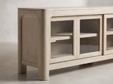 Close-up of the Albenga 71-Inch Weathered Mango Veneer Sliding Glass Door Media Console: the rounded bullnose corner, arched end panel and rounded leg in weathered mango