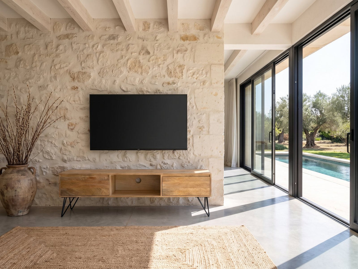 Alberobello Low Mango Media Console under a wall-mounted screen on a pale stone wall in a poolside villa