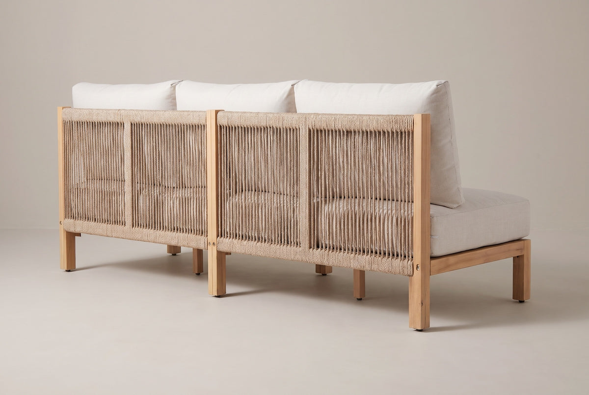 The Alcamo sofa from behind: the rope back panels between light teak back posts with bolt heads, the back cushions above and the square legs
