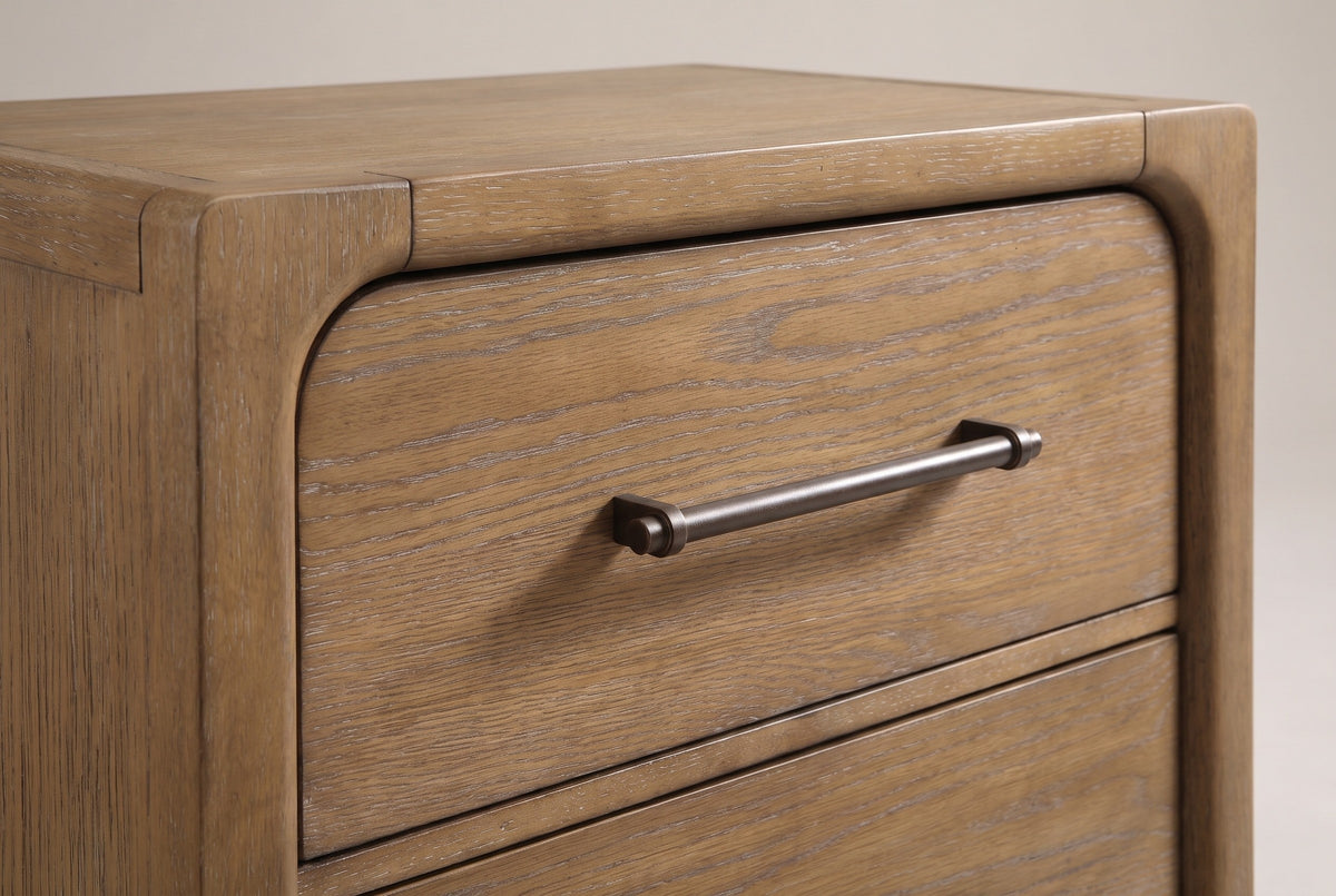 The top corner of the Alghero nightstand: rounded frame post and top rail, the top drawer with a rounded upper corner and a dark bronze bar pull