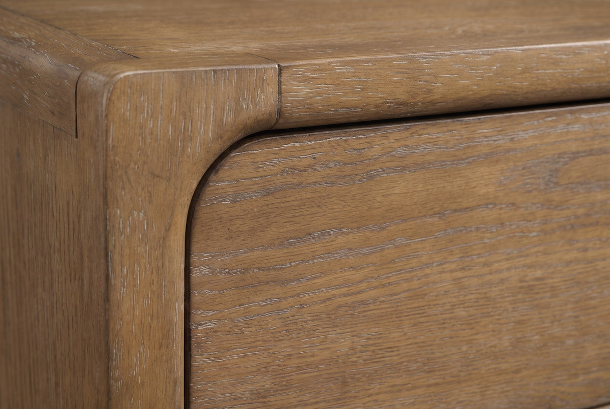 Close-up of the Alghero nightstand: warm brown oak with lightly limed open grain beside a thick rounded frame post