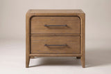 One Alghero nightstand in brown oak, front view on a light studio backdrop: two drawers with bronze bar pulls, a rounded frame and tapered legs