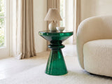 Alliste Blown Glass Hourglass Side Table with a lamp and a ceramic bowl beside a cream boucle armchair in a bright plaster room