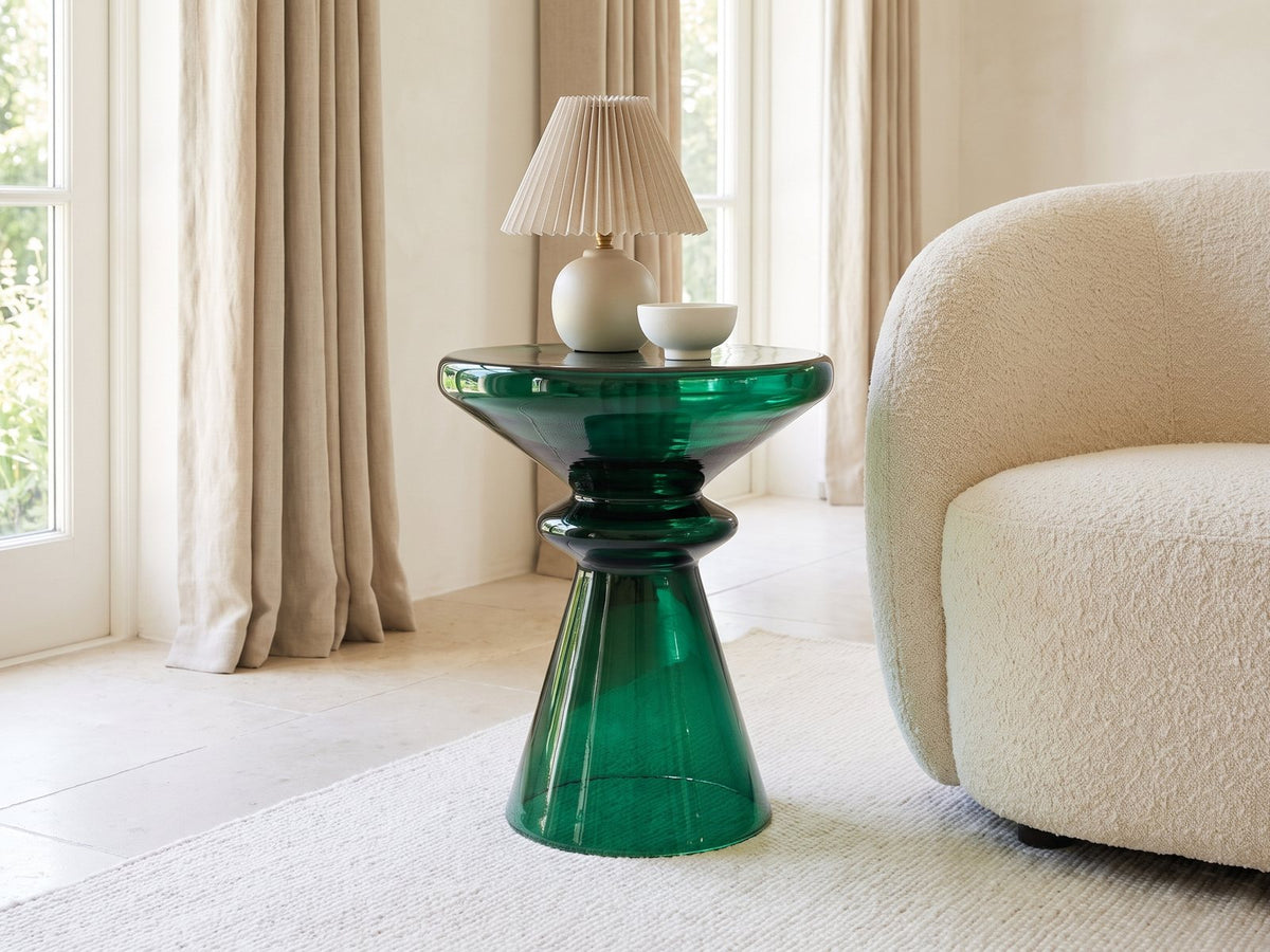 Alliste Blown Glass Hourglass Side Table with a lamp and a ceramic bowl beside a cream boucle armchair in a bright plaster room