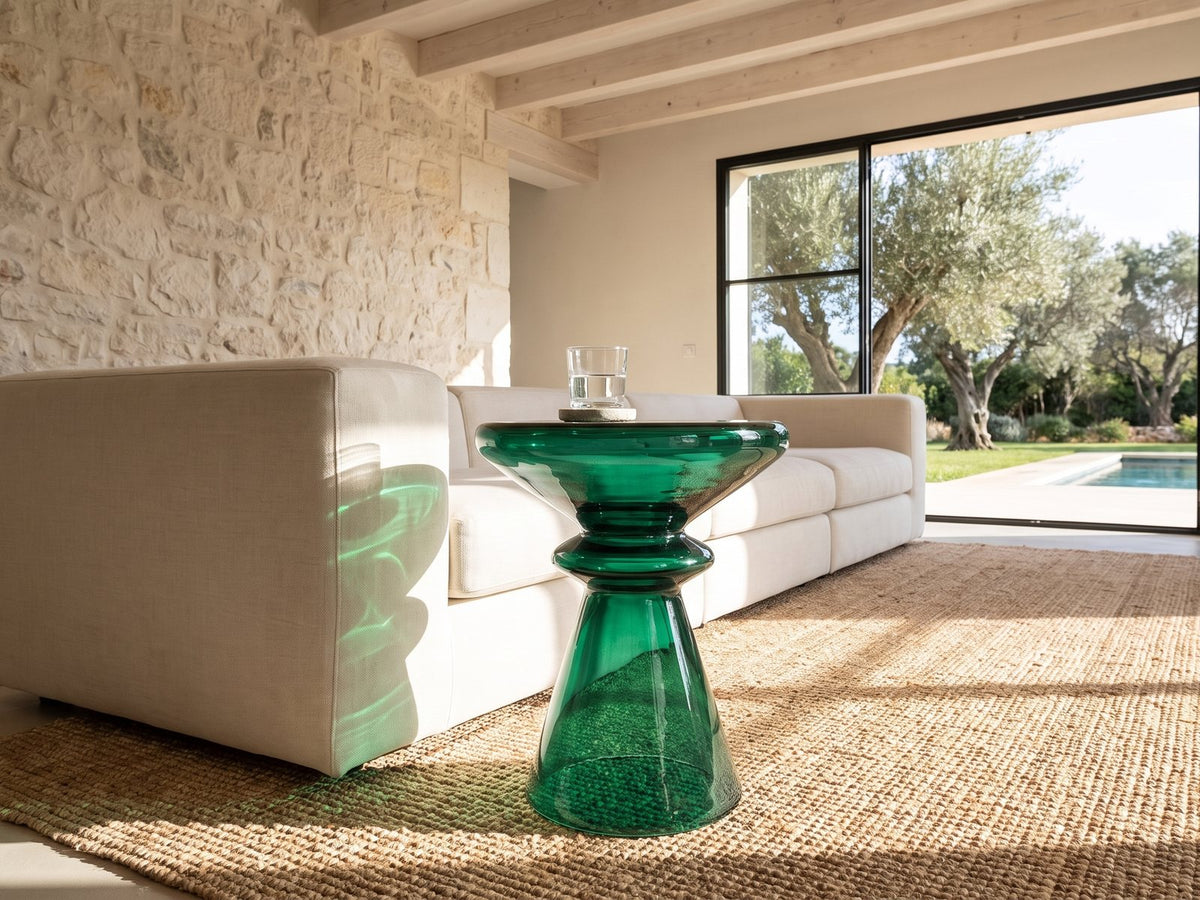 Alliste Blown Glass Hourglass Side Table beside a linen sofa in a poolside villa