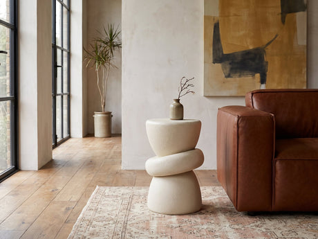 Altomonte Cream Fiberglass Stacked Side Table beside the arm of a cognac leather seat in an industrial loft