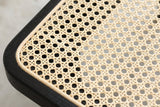Close-up of the natural rattan cane seat of the Anagni bench: an open weave of small eight-sided openings with a thin cane binding beside the black oak frame