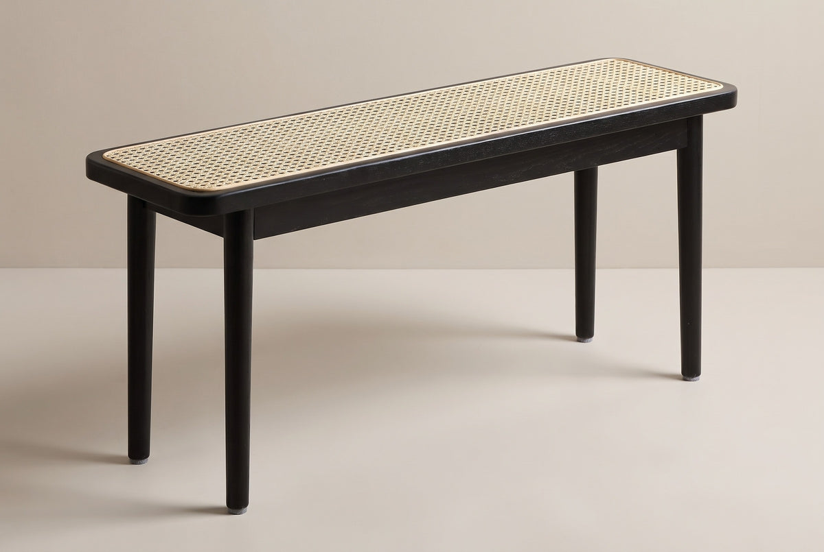 The Anagni bench in black oak with a natural cane seat, three-quarter view on a light studio backdrop