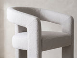 Close-up of the Anticoli 78-Inch Ebony Oak Pedestal Dining Set with 4 Boucle Armchairs: the horseshoe back band and slab arm of an armchair in light grey boucle