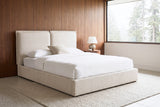 Anversa beige boucle bed against walnut wall panels in a mid-century bedroom near Portland, fir trees in the mist beyond the window