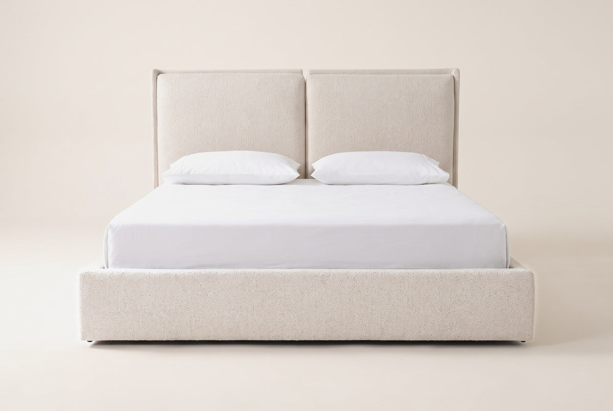 Anversa bed in beige boucle with a white mattress and pillows (not included), straight front view: two headboard panels over a low upholstered base