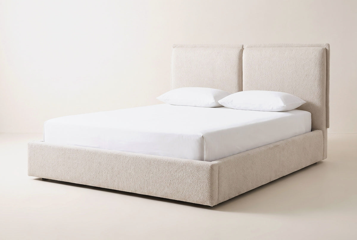 Anversa bed in beige boucle with a white mattress and pillows (not included), three-quarter view on a warm white studio backdrop