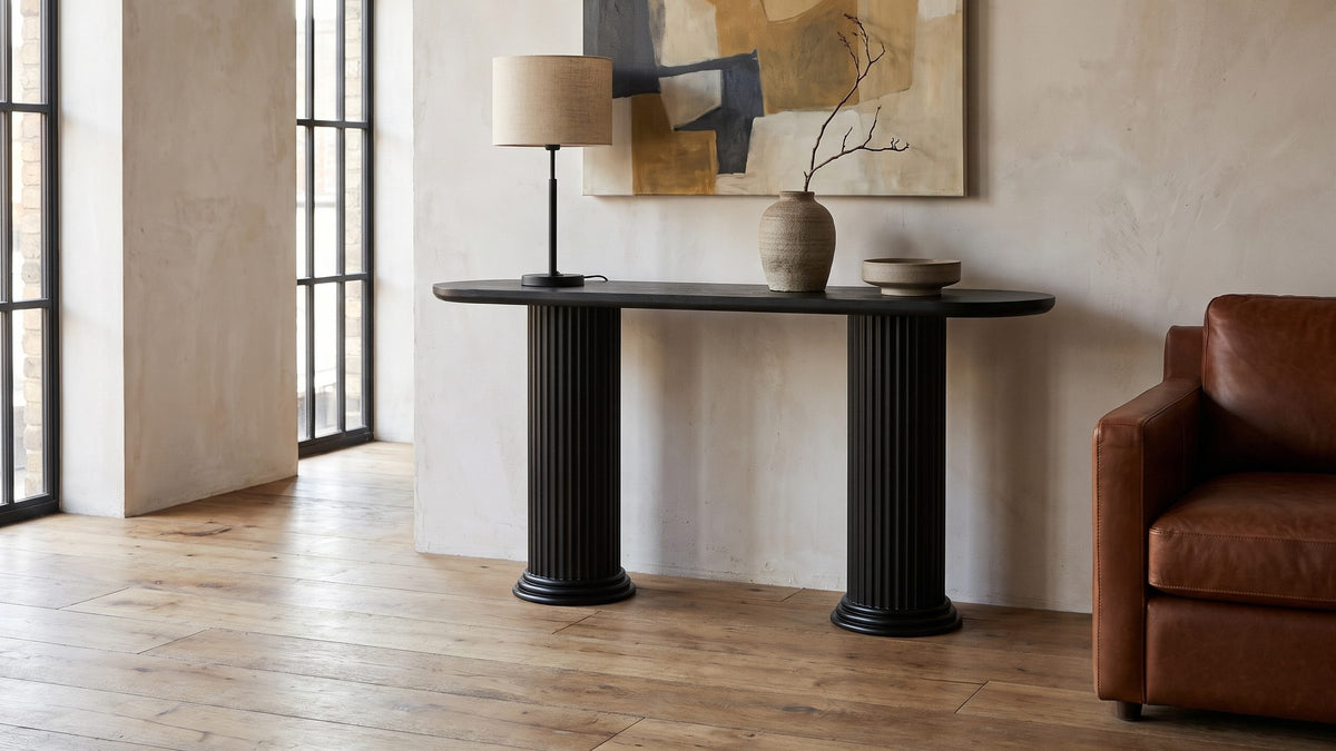 Two columns against a pale wall. - Imola Black Wood Veneer Oval Column Console Table