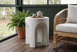 Aragona arched concrete side table with a teapot on a wooden tray on a screened porch in Atlanta, a forest-green beadboard wall and dark oak floor (chair and decor not included)