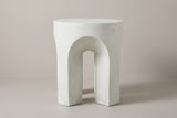 The Aragona side table seen straight on: one round-headed arch between two legs, antique white concrete