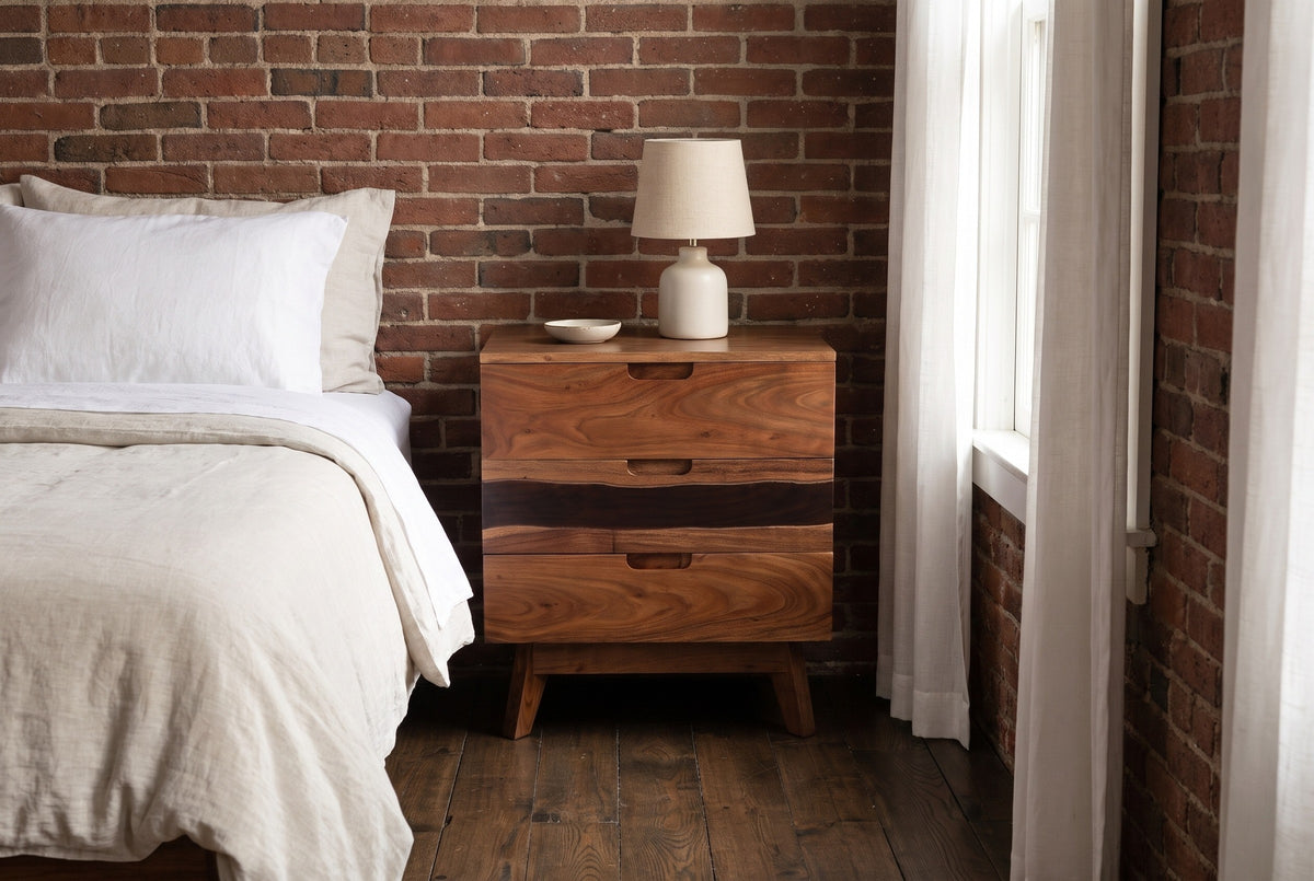 Arborea acacia nightstand against an exposed brick wall in a Boston apartment bedroom with dark oak floorboards