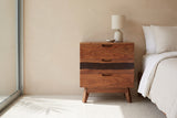Arborea acacia three-drawer nightstand with a ceramic lamp beside a bed in a Palm Springs bedroom with a sand-beige wall and a tall glass window