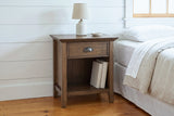 Arbus aged brown nightstand with a ceramic lamp and two linen books in a Vermont farmhouse bedroom with white shiplap walls and pine floors