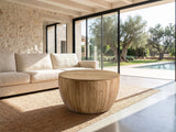 Arona 31.5-Inch Round Solid Fir Storage Drum Coffee Table on a jute rug in front of a linen sofa in a poolside villa