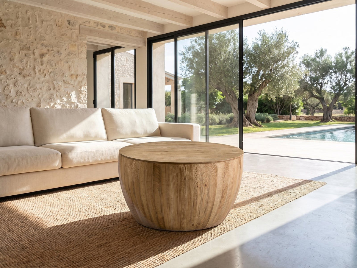 Arona 31.5-Inch Round Solid Fir Storage Drum Coffee Table on a jute rug in front of a linen sofa in a poolside villa