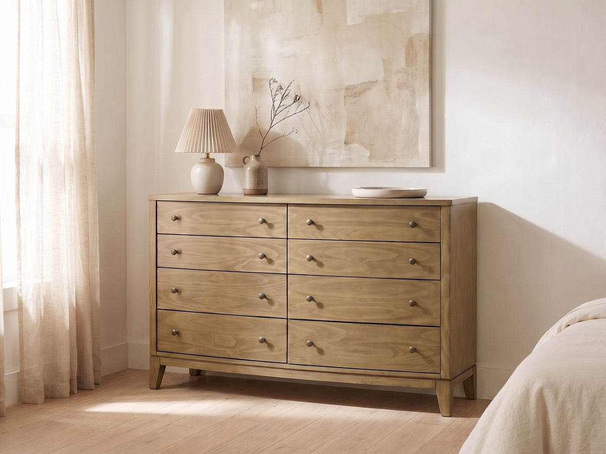 Arqua 61-Inch Natural Pine 8-Drawer Dresser against a plaster wall under an abstract canvas in a bright bedroom