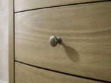 Close-up of the Arqua 61-Inch Natural Pine 8-Drawer Dresser: a round antique-nickel knob on a bowed pine drawer front