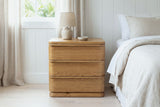 Arzachena oak nightstand with a ceramic lamp in a Laguna Beach cottage bedroom with white board-and-batten walls and sheer linen curtains