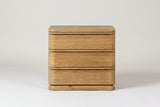 The Arzachena nightstand in natural oak, front view on a light studio backdrop