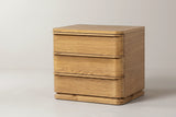 The Arzachena three-drawer nightstand in natural oak, three-quarter view on a light studio backdrop