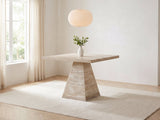 Asiago 40-Inch Square Faux Travertine Pyramid Pedestal Dining Table in a bright plaster dining room with linen curtains