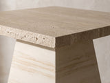 Close-up of the Asiago 40-Inch Square Faux Travertine Pyramid Pedestal Dining Table: the chiselled edge of the square top above the tapered pyramid pedestal
