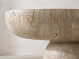 Close-up of the Asiago Faux Travertine Oval Mushroom Coffee Table: the short round pedestal under the deep curved edge of the top