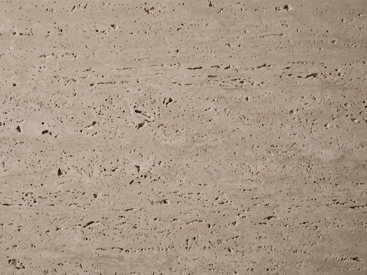 Close-up of the Asiago Faux Travertine Oval Mushroom Coffee Table: the pitted, matte travertine-look texture of the top
