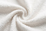Close-up of the white boucle on the Atessa bed: small, tight, curly loops gathered in a soft swirl