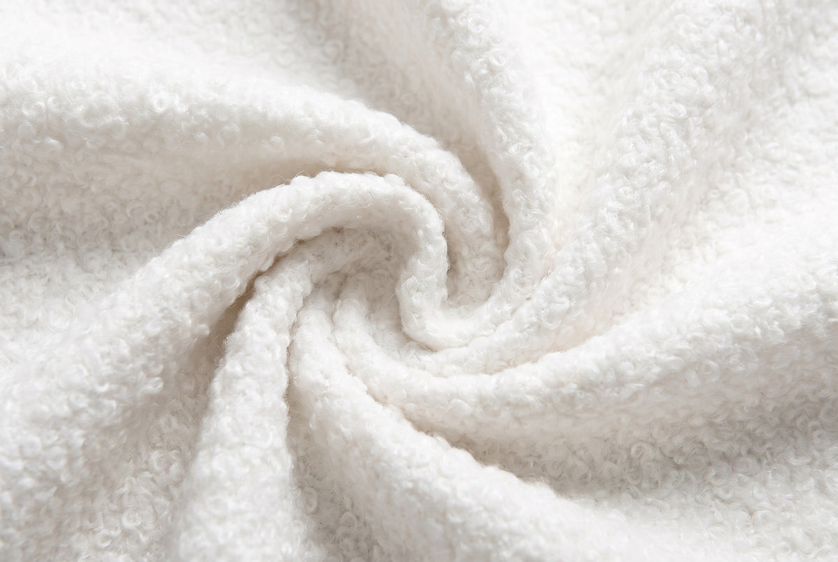Close-up of the white boucle on the Atessa bed: small, tight, curly loops gathered in a soft swirl