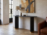 Atina Black Ash Oval Console Table against a plaster wall in an industrial loft