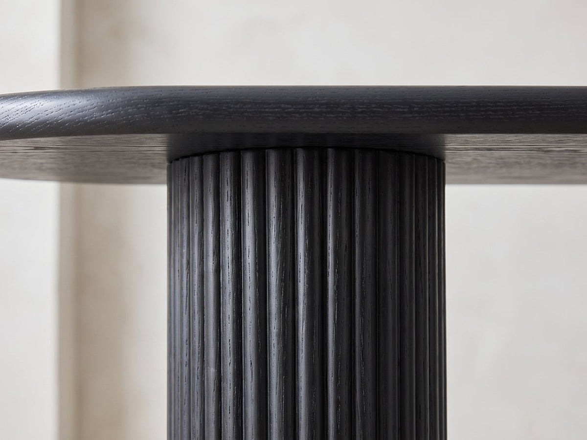 Close-up of the Atina Black Ash Oval Console Table: a reeded black ash leg meeting the rounded edge of the top