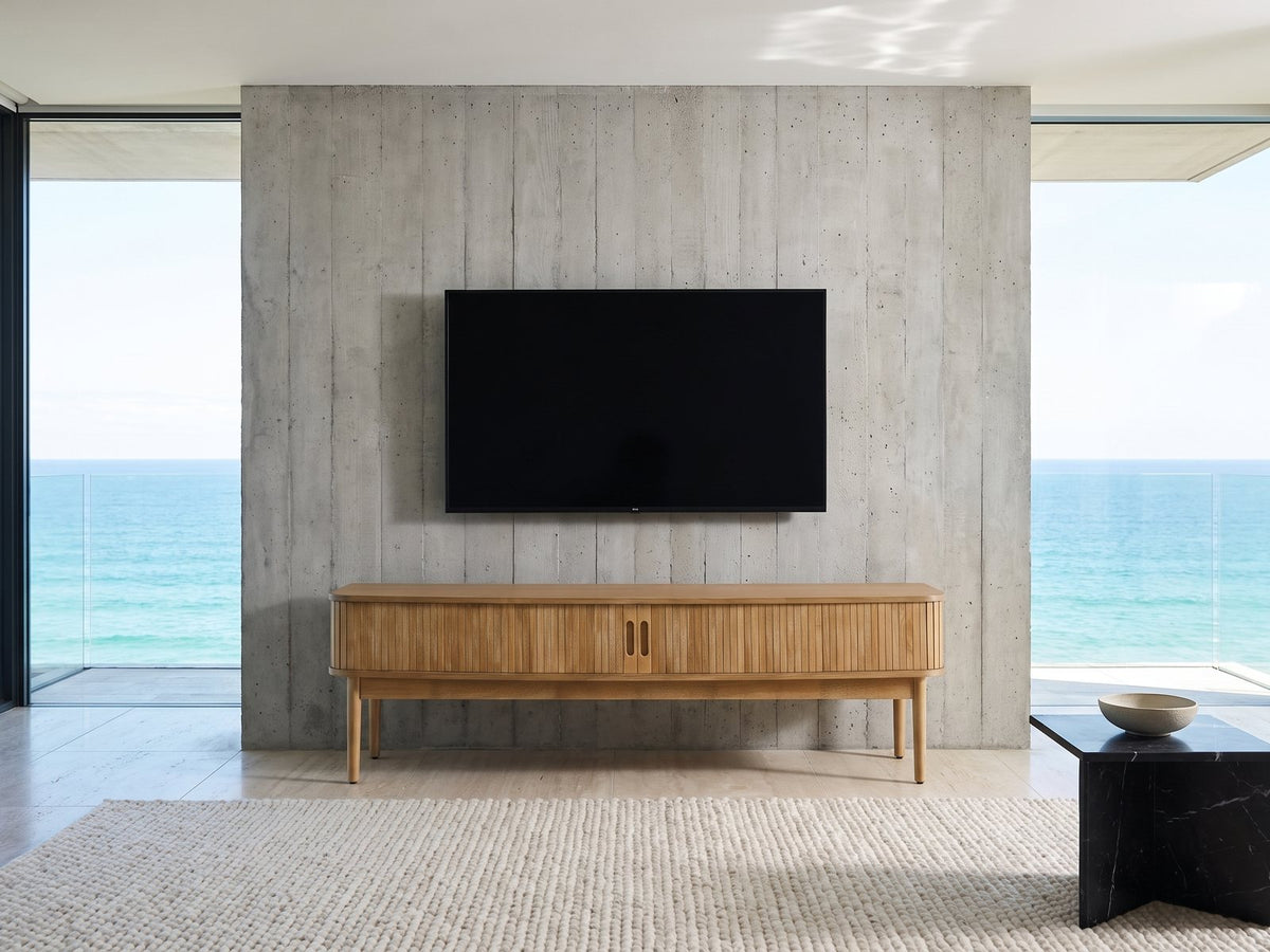 Atrani Reeded Curved Media Console under a wall-mounted screen in an oceanfront glass house