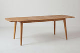 The Augusta dining table extended to 94.5 inches with its slatted center piece in place between the two halves, three-quarter view
