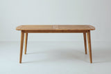 The Augusta dining table closed, seen from the long side: the thin slatted top, the apron and four tapered legs angling out toward the ends